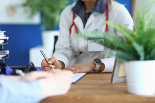 GP writing patient notes during a consultation, representing how EMMA by QuantumLoopAI helps NHS surgeries save time on admin and focus on better patient care.