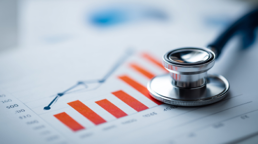 Stethoscope resting on a financial chart with red bar graphs, symbolising the effect of rising National Insurance contributions on NHS GP surgery finances and how AI tools like EMMA by QuantumLoopAI improve efficiency and reduce costs.